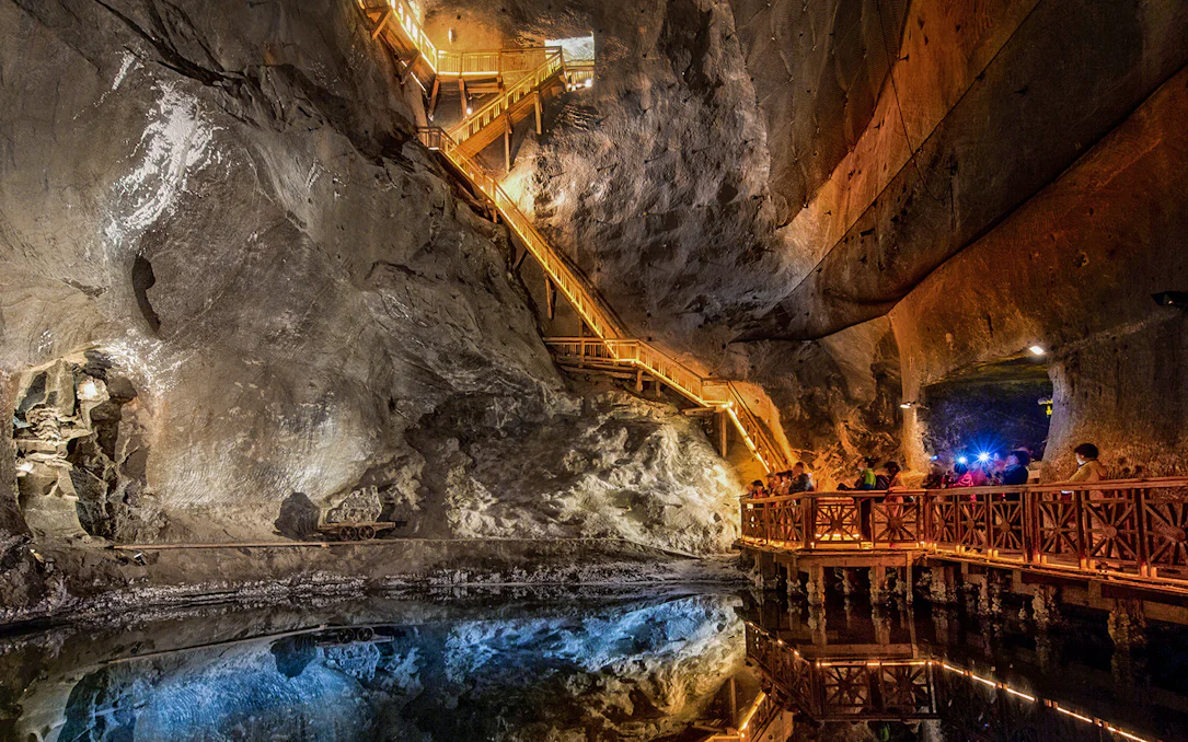 Visitors exploring the illuminated salt lake in the Wieliczka Salt Mine, Poland.