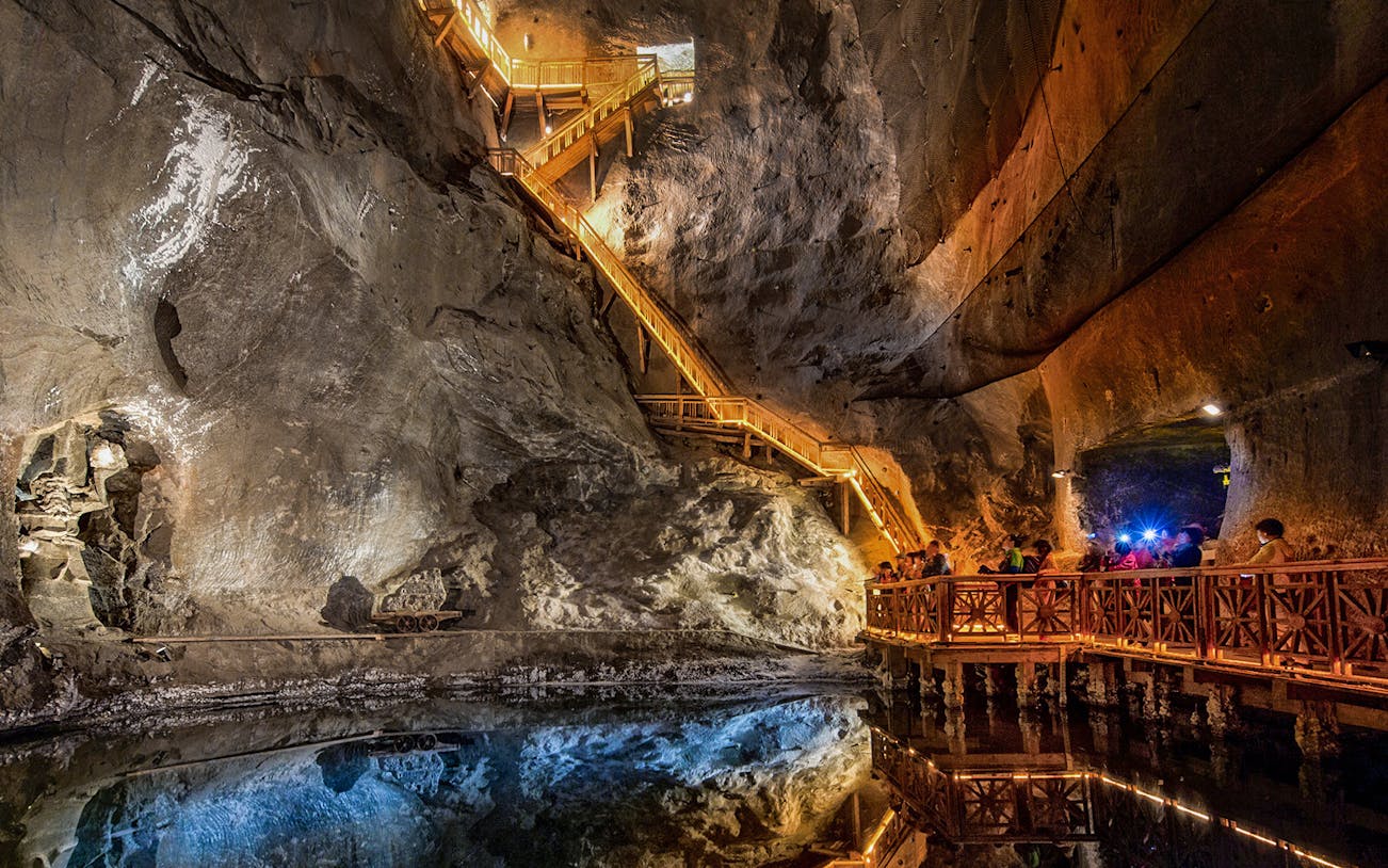 Visitors exploring the illuminated salt lake in the Wieliczka Salt Mine, Poland.