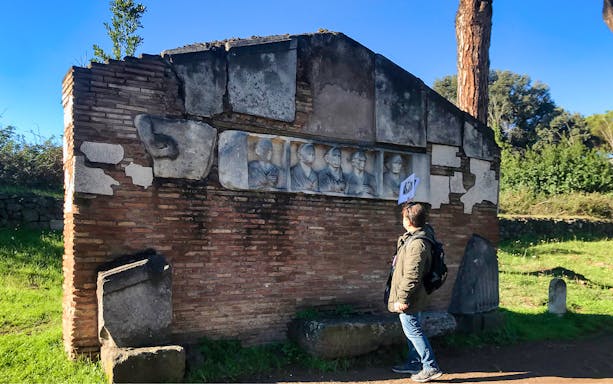 Ancient Roman relief on Appia Antica viewed by a tourist during an e-bike guided tour.