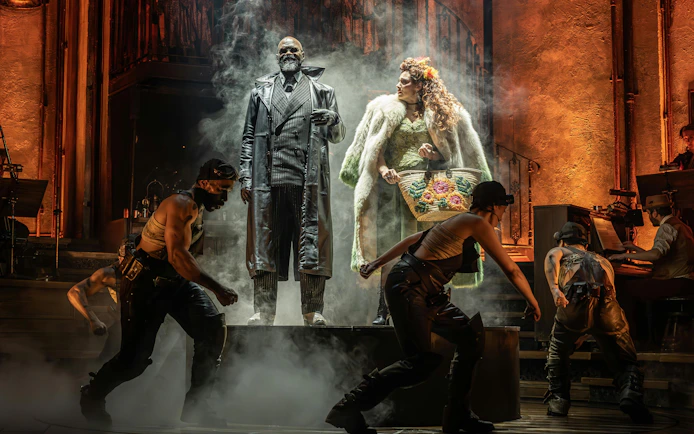 Stage performance of Hadestown in West End with actors in dramatic poses.
