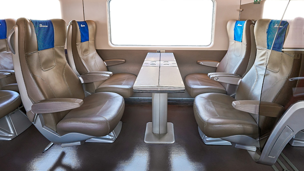 Trenitalia business class seats with table in train interior.