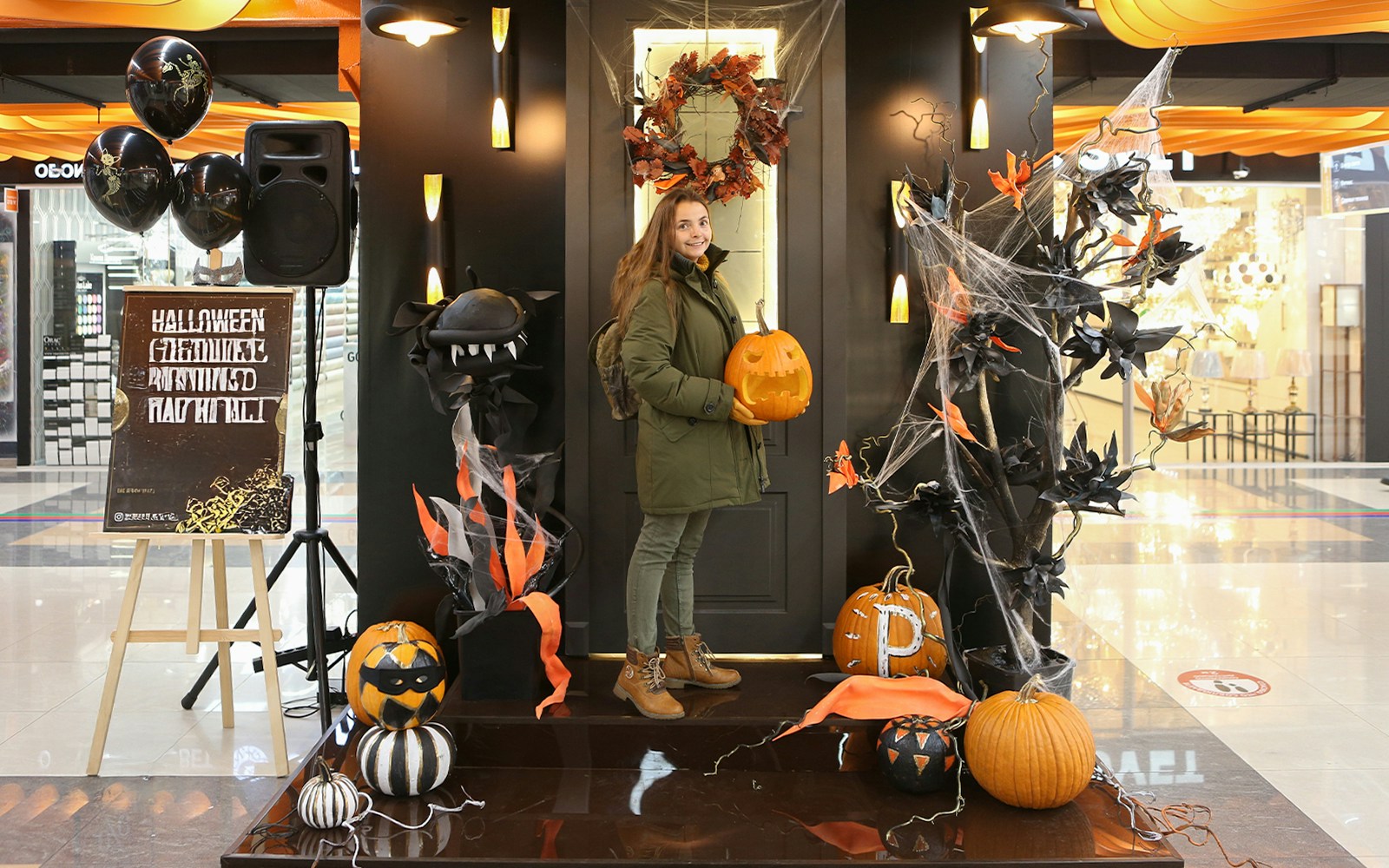 Halloween decorations in Las Vegas mall with pumpkins, cobwebs, and a person holding a carved pumpkin.