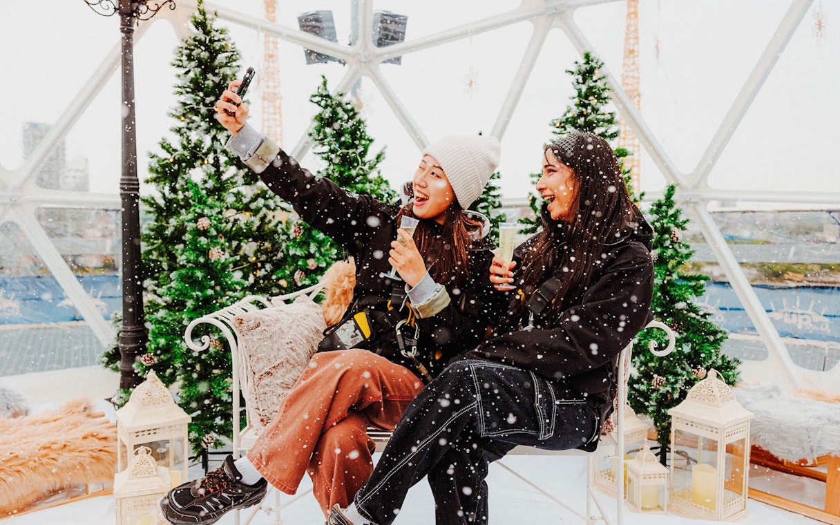 Guests enjoying the Up at the O2 Snow Globe Experience with snow and festive decor.
