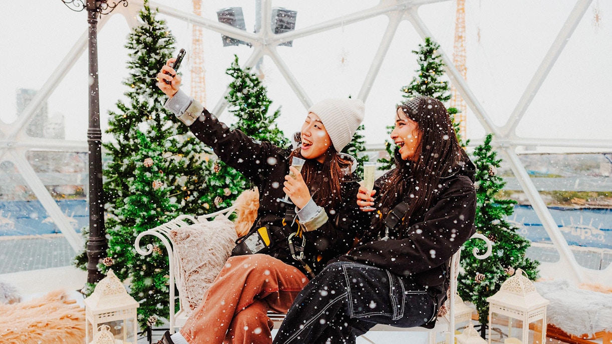 Guests enjoying the Up at the O2 Snow Globe Experience with snow and festive decor.