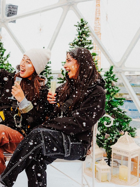 Guests enjoying the Up at the O2 Snow Globe Experience with snow and festive decor.