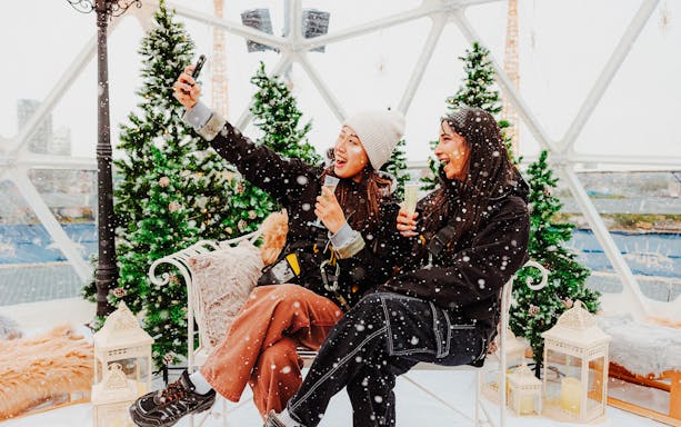 Guests enjoying the Up at the O2 Snow Globe Experience with snow and festive decor.