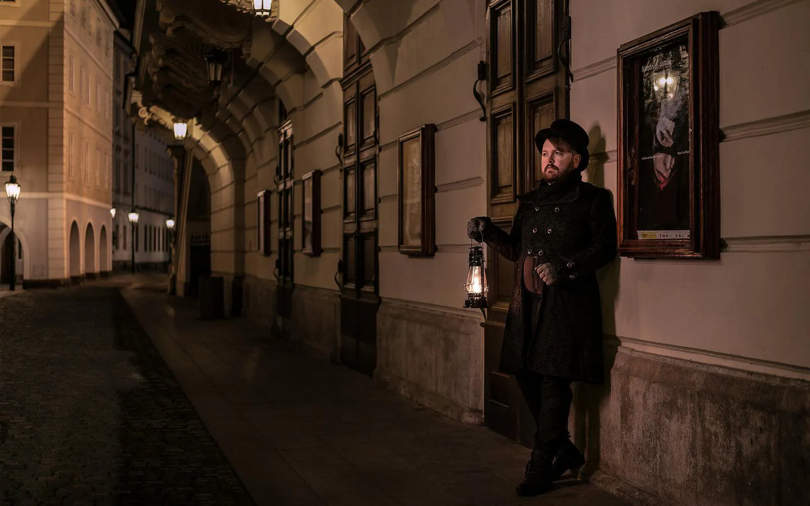 Guide holding lantern in Prague's Old Town during night-time ghost tour.
