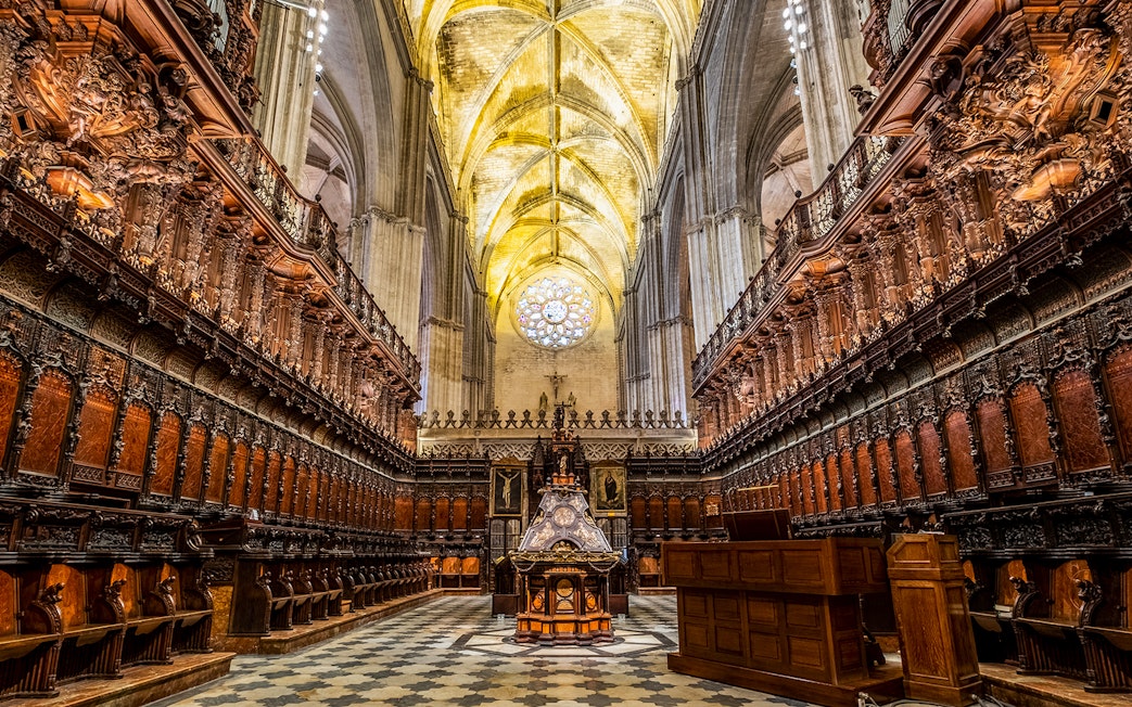 Cathedral interior with ornate wooden choir stalls and vaulted ceiling, Seville.