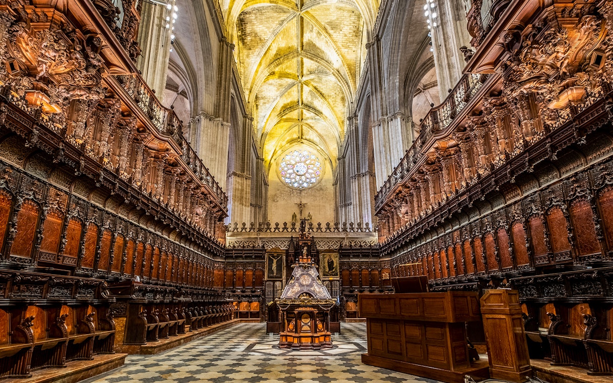 Cathedral interior with ornate wooden choir stalls and vaulted ceiling, Seville.