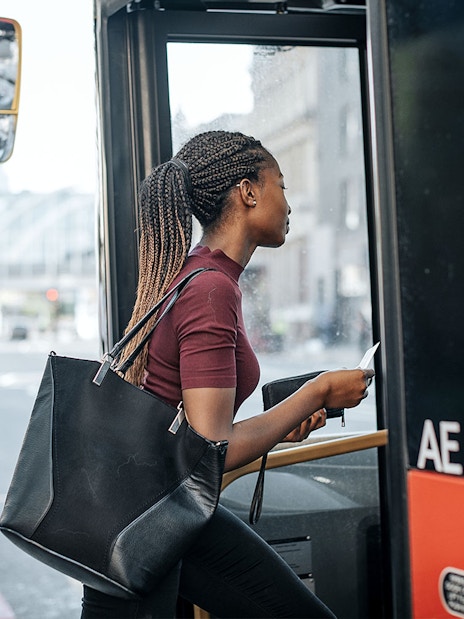 Person boarding a city bus with a Sky-Bus One-Way Transfer Travel Pass.