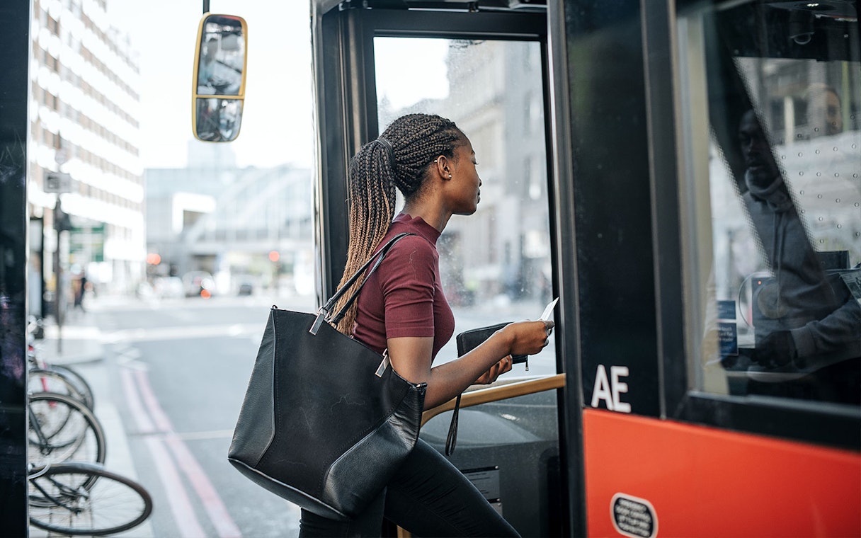 Person boarding a city bus with a Sky-Bus One-Way Transfer Travel Pass.