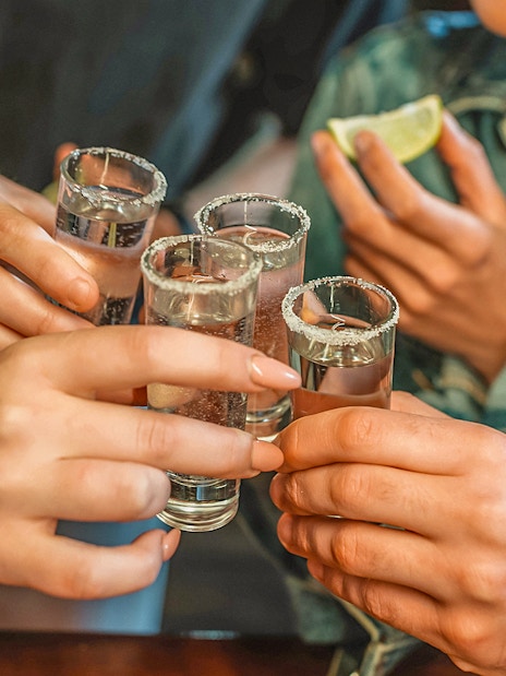 Friends toasting with shot glasses at a nightclub.