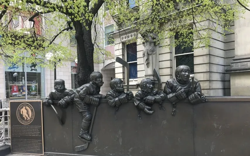 Hockey player statues on a wall in Old Town Toronto during a self-guided city exploration game.