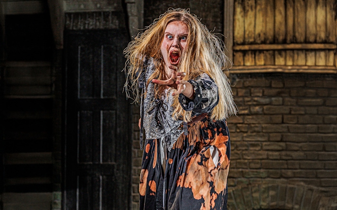 Actor in costume performing at London Dungeon attraction.