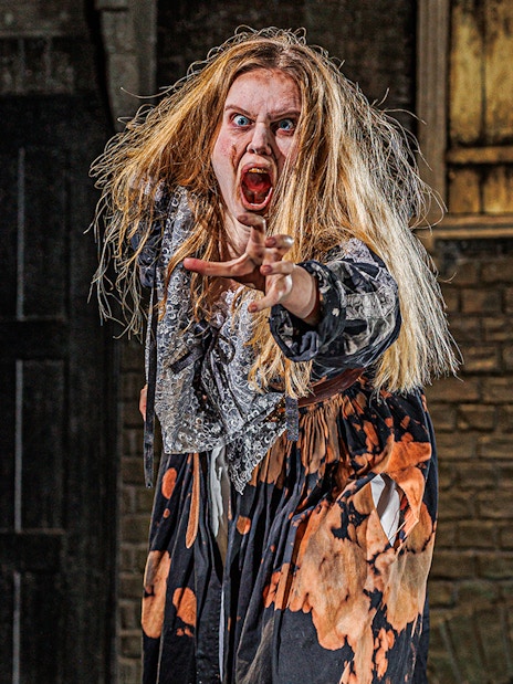 Actor in costume performing at London Dungeon attraction.