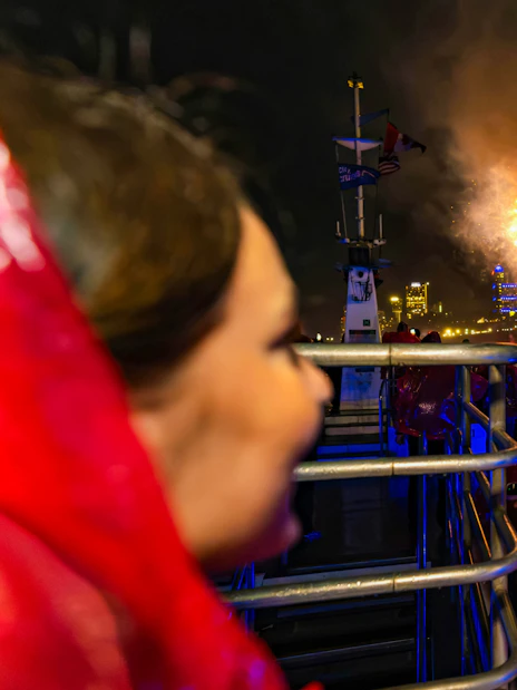 Tourists on a boat at Niagara Falls watching fireworks at night.