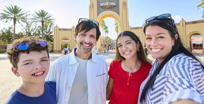 Guests smiling in front of Universal Studios Florida arch, Orlando.