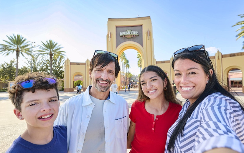 Guests smiling in front of Universal Studios Florida arch, Orlando.
