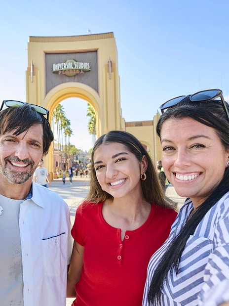Guests smiling in front of Universal Studios Florida arch, Orlando.