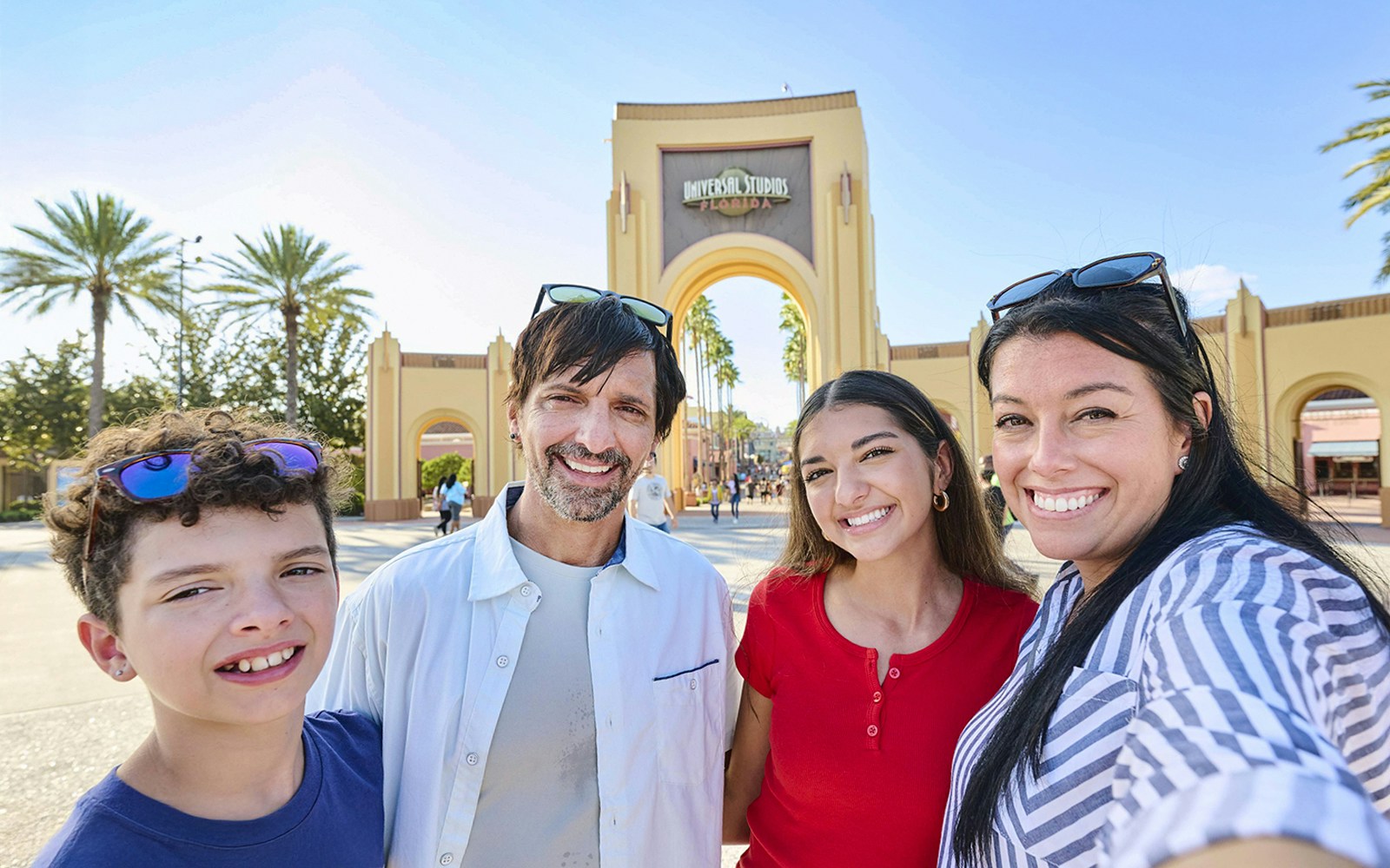 Guests smiling in front of Universal Studios Florida arch, Orlando.
