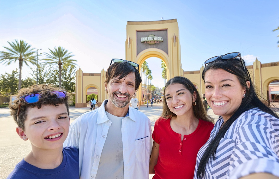 Guests smiling in front of Universal Studios Florida arch, Orlando.