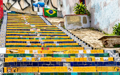 Colorful tiled Selaron Steps in Rio de Janeiro, Brazil, with Brazilian flag in background.