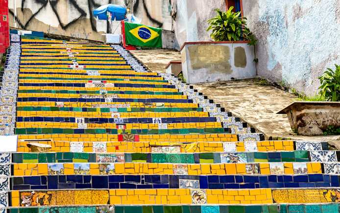 Colorful tiled Selaron Steps in Rio de Janeiro, Brazil, with Brazilian flag in background.