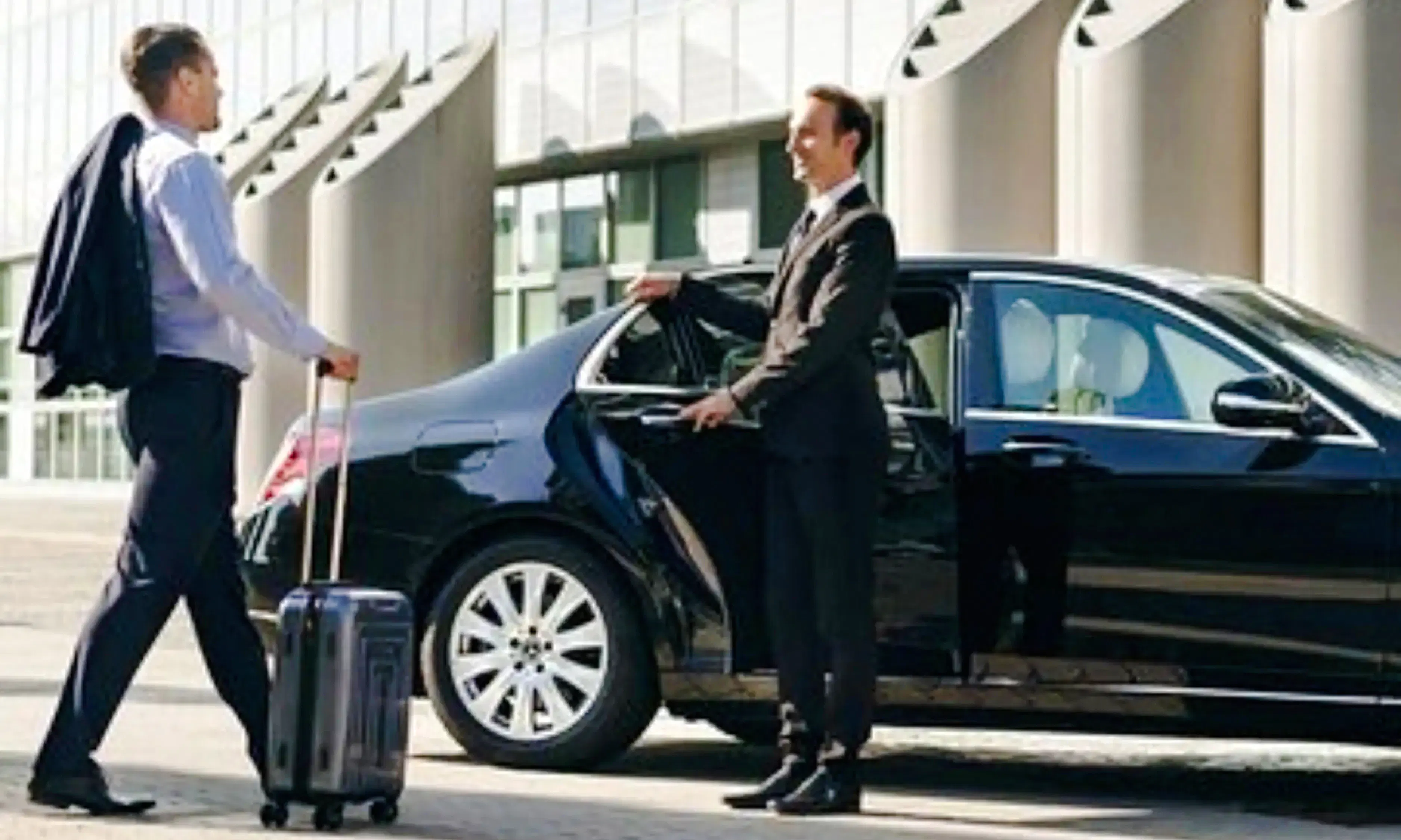 Man with luggage approaches chauffeur holding car door for AlUla private airport transfer, Medina.