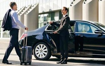 Man with luggage approaches chauffeur holding car door for AlUla private airport transfer, Medina.