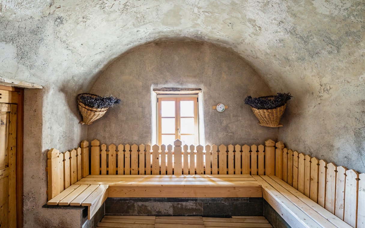 Rustic sauna room at QC Terme Bagni Vecchi di Bormio with wooden benches and window.