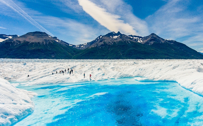 Tourists exploring Perito Moreno Glacier near a small lake in Argentina.