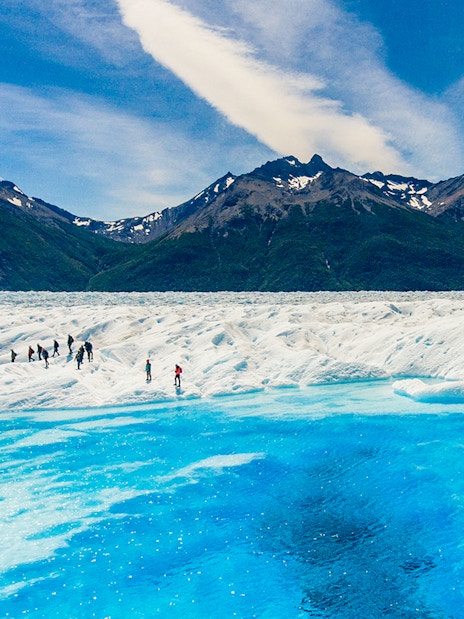 Tourists exploring Perito Moreno Glacier near a small lake in Argentina.