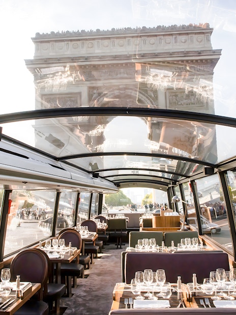 Bustronome Paris interior with dining setup and view of Arc De Triomphe.
