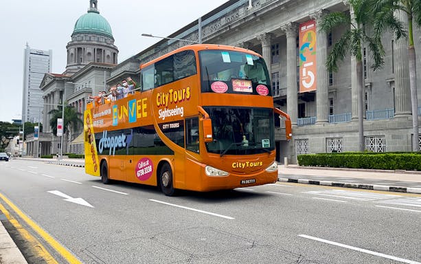 Open-top FunVee bus touring past historic buildings in Singapore.