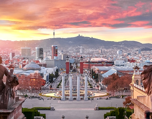 Sunset view over Barcelona from Montjuïc, highlighting cityscape and harbor.