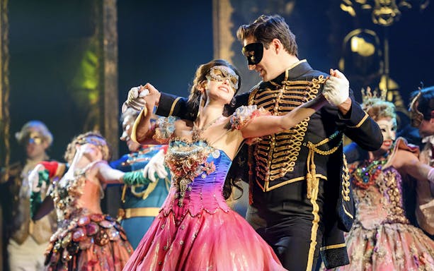 Couple in masquerade costumes dancing at The Phantom of the Opera musical in Vienna.