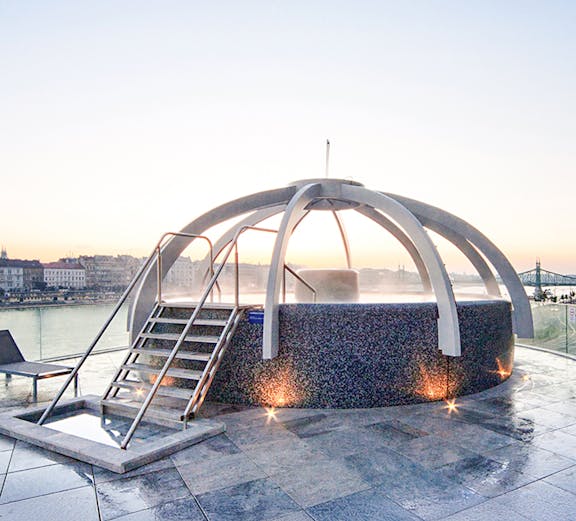 Rooftop pool at Rudas Bath in Budapest with city skyline in the background.