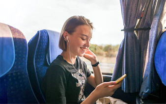 Traveler enjoying music on a coach transfer journey.