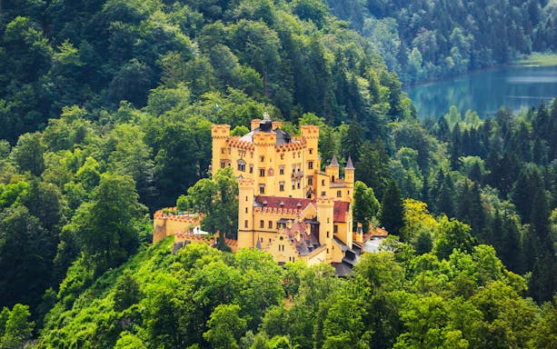Hohenschwangau Castle surrounded by lush forest, Bavaria, Germany.