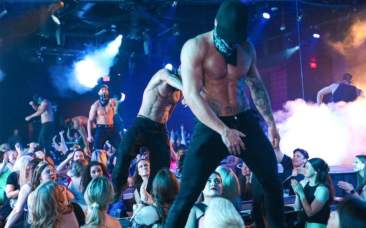 Performers on stage at Australia's Thunder from Down Under show, entertaining a lively audience.