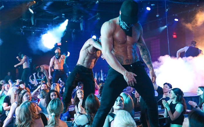 Performers on stage at Australia's Thunder from Down Under show, entertaining a lively audience.