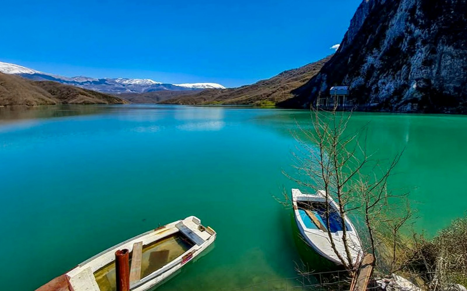 Boats on Bovilla Lake with mountain backdrop in Albania.