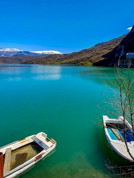 Boats on Bovilla Lake with mountain backdrop in Albania.