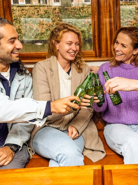 Guests toasting with beer on the Heineken Flagship Canal Cruise in Amsterdam.