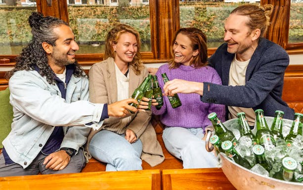 Guests toasting with beer on the Heineken Flagship Canal Cruise in Amsterdam.