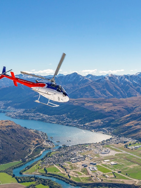 Helicopter flying over Queenstown with view of mountains and lake on Milford Sound Fly-Cruise-Heli Tour.