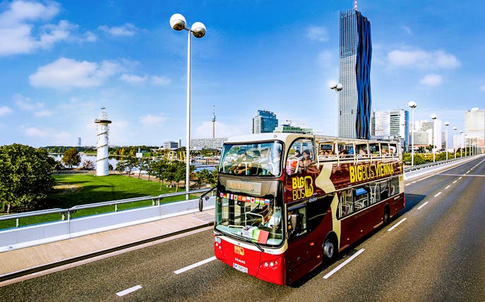 Big Bus tour passing DC Tower 1 in Vienna, showcasing city skyline.