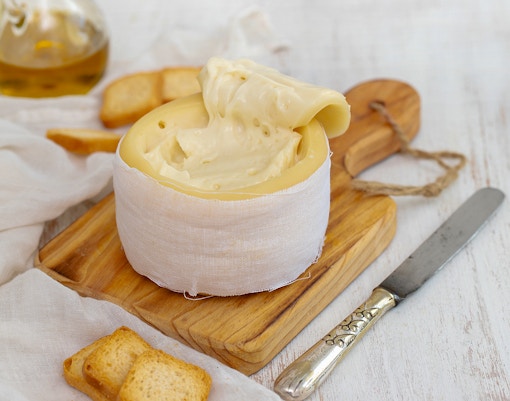 Portuguese cheese on a wooden board with bread and knife.
