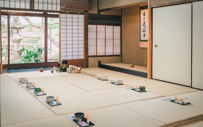 Traditional tea ceremony setup in a 100-year-old Machiya townhouse with tatami mats and tea utensils.