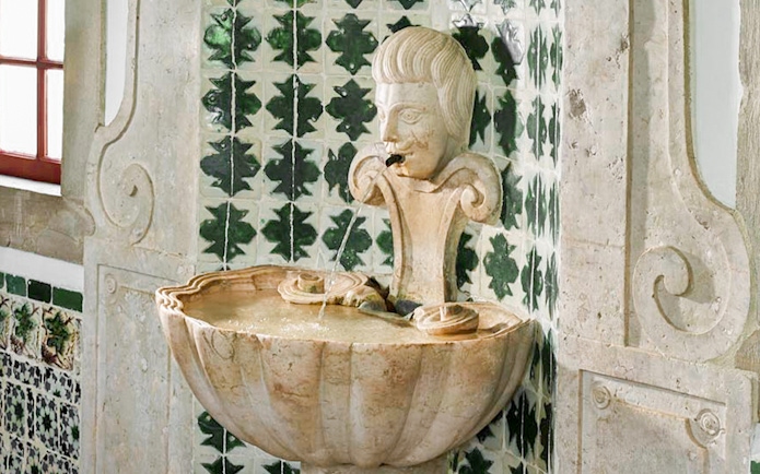 Stone fountain with carved face in the Archers Room, National Palace of Sintra.